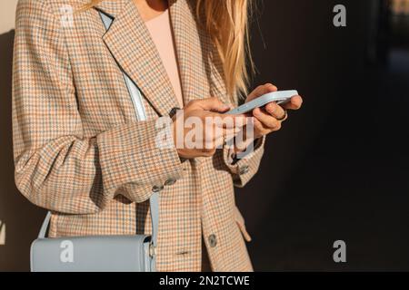 Close-up of a stylish businesswoman standing in the street using her mobile phone, Belarus Stock Photo