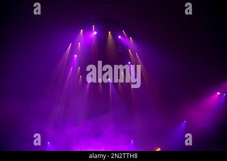 Purple rays from stage spotlights on a dark background. Stock Photo