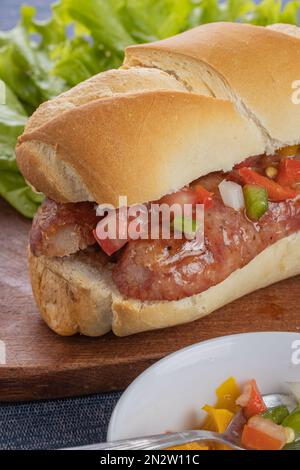 Close up of a choripan, typical argentine sandwich with chorizo and creole sauce. Stock Photo