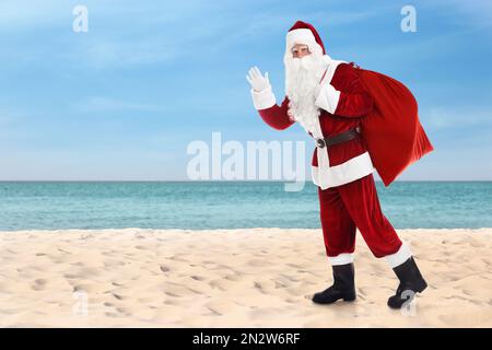 Santa Claus with sack on sandy beach. Space for text Stock Photo