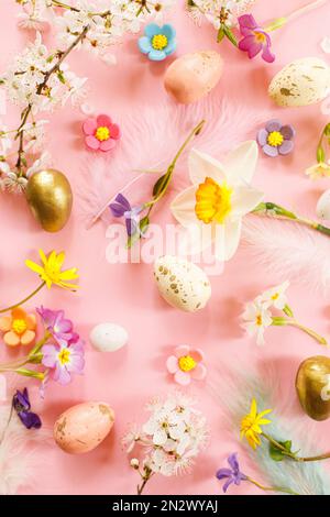 Stylish Easter eggs, spring flowers and feathers flat lay on pink background. Happy Easter! Greeting card template. Modern floral colorful holiday ban Stock Photo