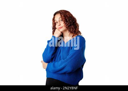 Young caucasian woman wearing sweater standing isolated over white background touches chin with fist and looks very bored. Doesn't believe the lies an Stock Photo