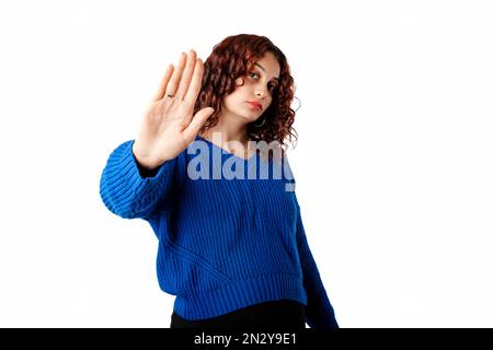 Beautiful woman wearing blue knitted sweater standing isolated over white background doing stop sing with palm of the hand. Warning expression with ne Stock Photo