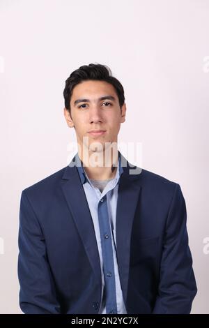 A teenage boy wearing a navy blue suit and blue shirt with white background looking at the camera. Stock Photo