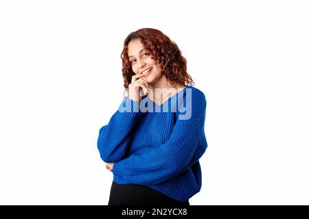 Portrait of woman wearing blue knitted sweater standing isolated over white background finger touch teeth ceramic wonder. Smiles at the camera with ho Stock Photo