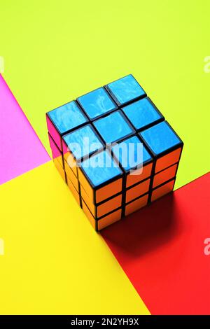 Rubik's cube blue side on a pink green red yellow table. Stock Photo