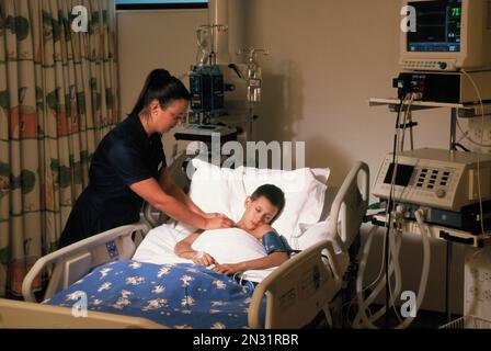 Young boy patient with nurse in hospital intensive care unit. Stock Photo