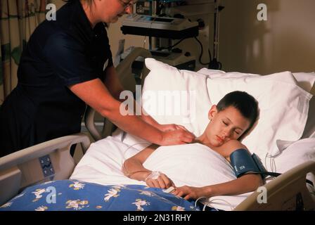 Young boy patient with nurse in hospital intensive care unit. Stock Photo
