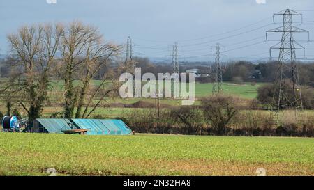 Electricity pylons carrying high tension cabling, supplying the national grid, dominating farmland in Devon, England Stock Photo