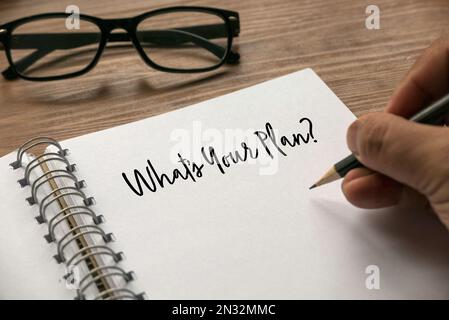 A hand writing a question What's Your Plan? on a notebook. Stock Photo