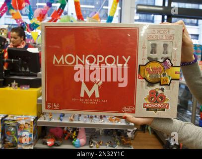 A saleswoman displays the new Monopoly board game version at a toy store near the Champs Elysees avenue in Paris, Wednesday, Feb. 4, 2015. The French version of Monopoly is celebrating its 80th year by slipping cash into 80 boxes of the game. One box will have the full complement in real money 20,580 euros ($23,600) as well as the Monopoly money needed to actually play the game, one of the most popular in France. 79 other boxes will have smaller amounts according to Hasbro. (AP Photo/Michel Euler)
