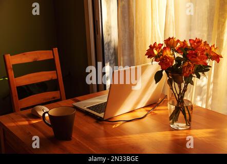 Simple candid workplace at home with laptop computer in sunset light. Remote working from home in comfortable working environment. Stock Photo