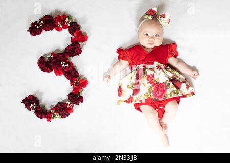 Little newborn baby girl in red dress. 3 month old baby Stock Photo