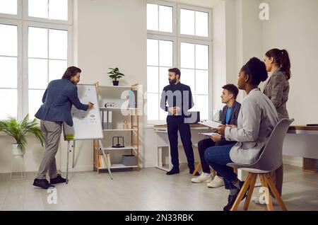 Multiethnic people office workers of marketing company or startup drawing graphs on flipchart Stock Photo