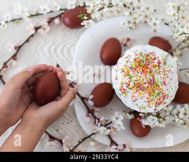 Red eggs for Easter, Easter traditional menu, hands holding painted eggs Stock Photo
