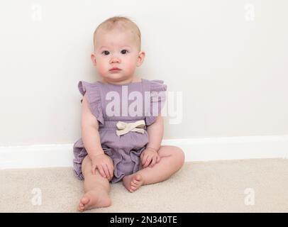 Cute caucasian baby girl learning how to sit at 9 month old Stock Photo