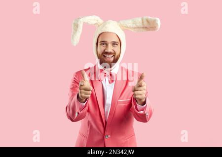 Happy guy wearing funny Easter bunny costume smiling and pointing fingers at camera Stock Photo