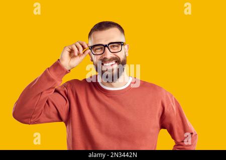 Happy smiling young man in glasses and sweatshirt standing isolated on yellow background Stock Photo