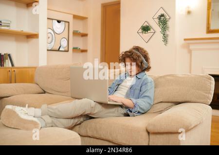 A curly-haired boy spending time on internet and looking involved Stock Photo