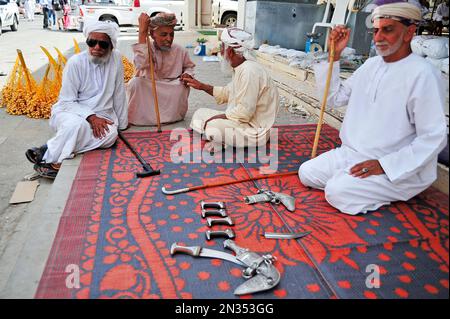 Khanjars on display at the gun market in Nizwa, Oman - Men in traditional dress Stock Photo
