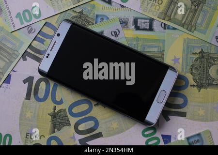 smartphone lies on 100 euro banknotes Stock Photo