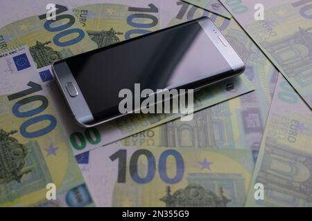smartphone lies on 100 euro banknotes Stock Photo