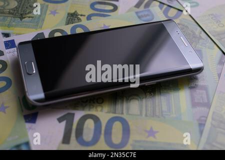 smartphone lies on 100 euro banknotes Stock Photo