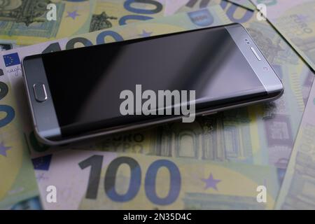 smartphone lies on 100 euro banknotes Stock Photo