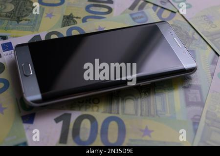 smartphone lies on 100 euro banknotes Stock Photo