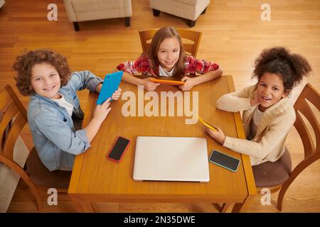 A group of kids with gadgets in hands sitting at the table Stock Photo