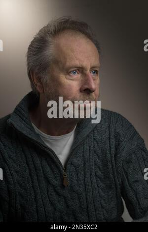 Head shot head and shoulders portrait of attractive mature senior older white man  with beard wearing a chunky knitted cable textured sweater jumper Stock Photo