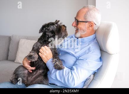 Senior man holding a dog in a retirement home Stock Photo