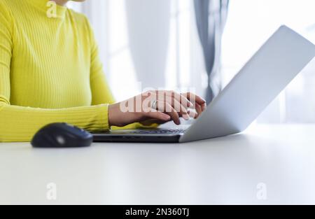 Young woman typing on laptop. Close up photo of unrecognizable female person using modern notebook computer for work Stock Photo