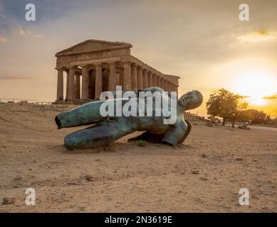 Icarus, modern bronze sculpture, falled in front of the Temple of Concordia, Valley of Temples, Agrigento province, Sicily, Italy Stock Photo