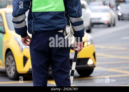 Police officer standing with traffic rod on cars background. Policeman patrol the city street Stock Photo