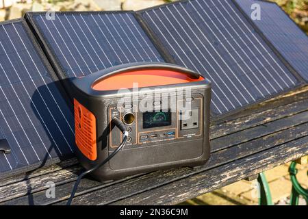 Solar generator battery pack being charged by panels in the sun Stock Photo
