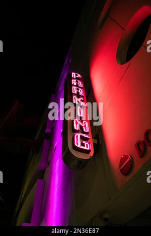 Night street photo of neon parking sign on the side of a building in South Beach, Florida. Stock Photo