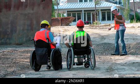Construction engineers discussing site issues, men in wheelchairs with spinal cord injuries; Plymouth, Massachusetts, United States of America Stock Photo
