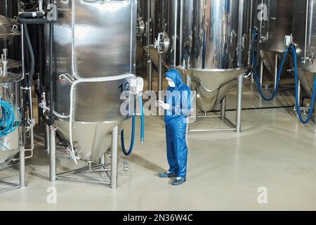 Wide angle view at factory workshop with storage tanks and worker wearing protective suit, copy space Stock Photo