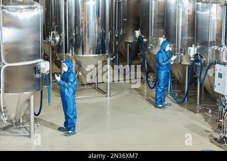 Wide angle view at factory workshop with two workers operating storage tanks, copy space Stock Photo