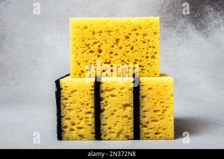 A stack of yellow dishwashing sponges close-up on a neutral gray background. Gentle dishwashing. House cleaning. Stock Photo