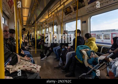 Families travel on a busy London Underground District Line train carriage at the weekend in central London, England, United Kingdom Stock Photo