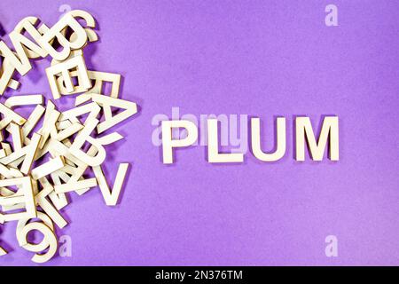 PLUM in wooden English language capital letters spilling from a pile of letters on a purple background Stock Photo