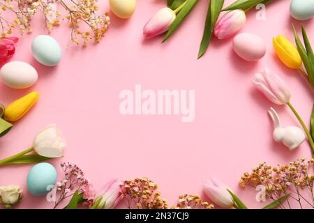 Frame made of Easter eggs and beautiful flowers on pink background Stock Photo