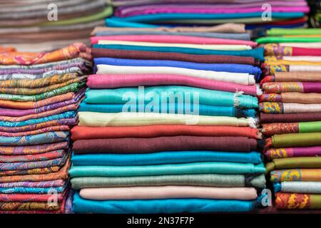 Retail place, retail display. Multicolored fabric scarves, shawls, stoles, real store shelf, selective background Stock Photo