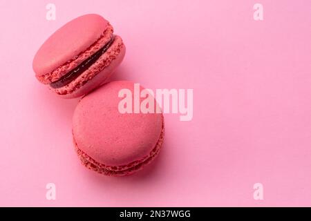 Two pink french macarons isolated on pink background. Stock Photo