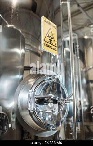 Vertical background image of Warning biohazard sign on steel storage tank in chemical factory Stock Photo