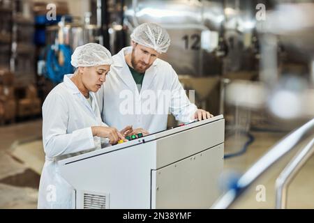 Portrait of two workers wearing lab coats operating equipment at food factory, copy space Stock Photo