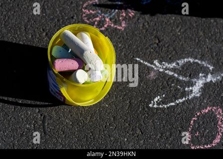 Bucket with colorful street paint chalk on tar road Stock Photo