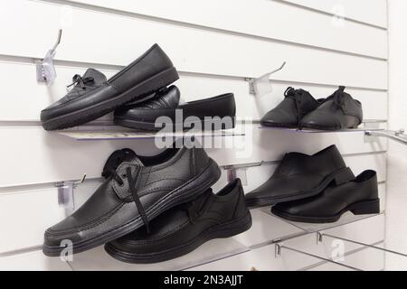 Men shoes for the deceased in a funeral goods store. An exhibition with black men shoes for funerals. Stock Photo